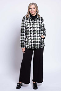 Woman in black and white houndstooth coat with relaxed posture, front view