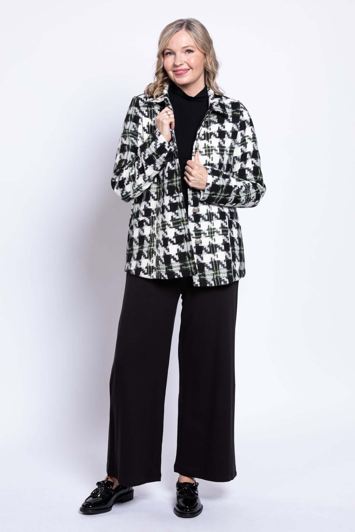 Woman holding collar of black and white houndstooth coat smiling