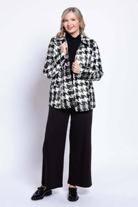 Woman holding collar of black and white houndstooth coat smiling