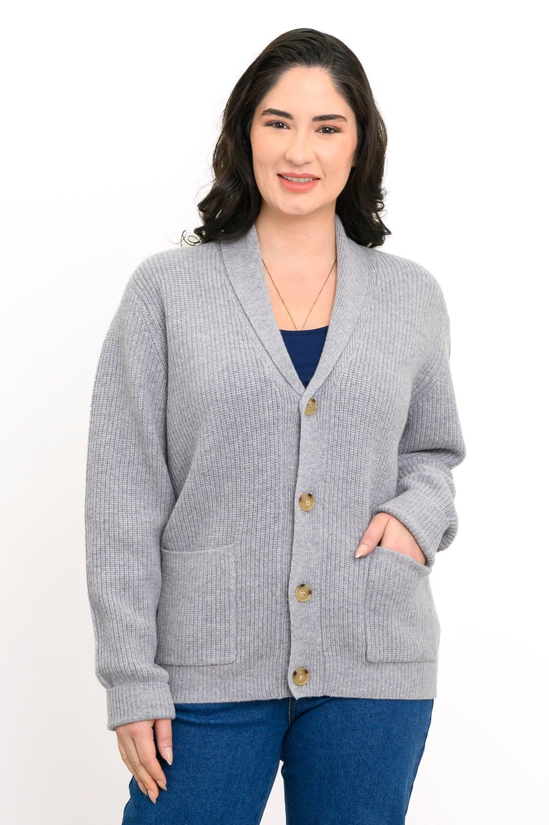 Woman wearing grey knit cardigan and denim pants on a white background, front view