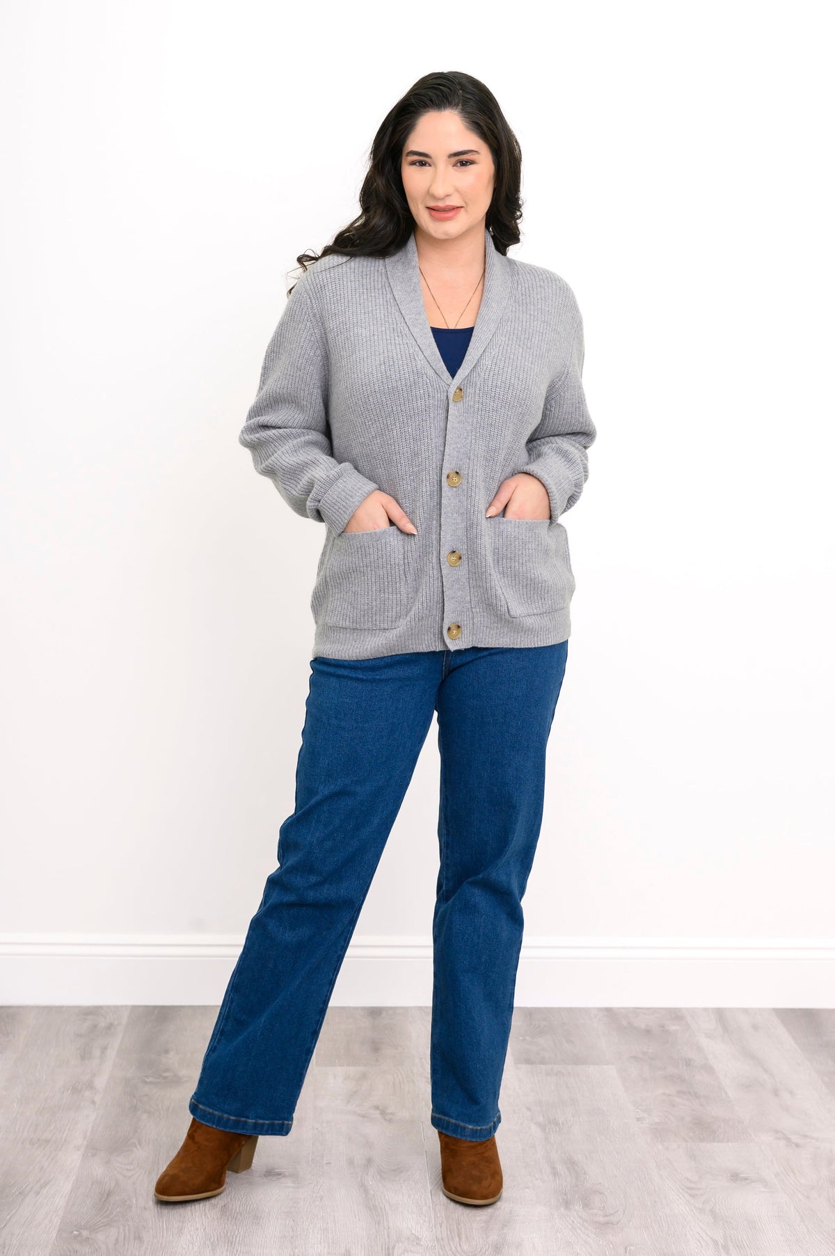 Full body view of woman in grey cardigan with foldover neckline and tortoise shell buttons