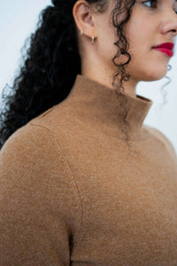 Close-up detail of the camel brown mock neck sweater's fabric and collar