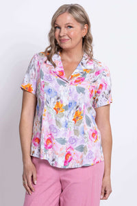 Close-up front view of woman wearing button-up blouse with collar and pastel floral print