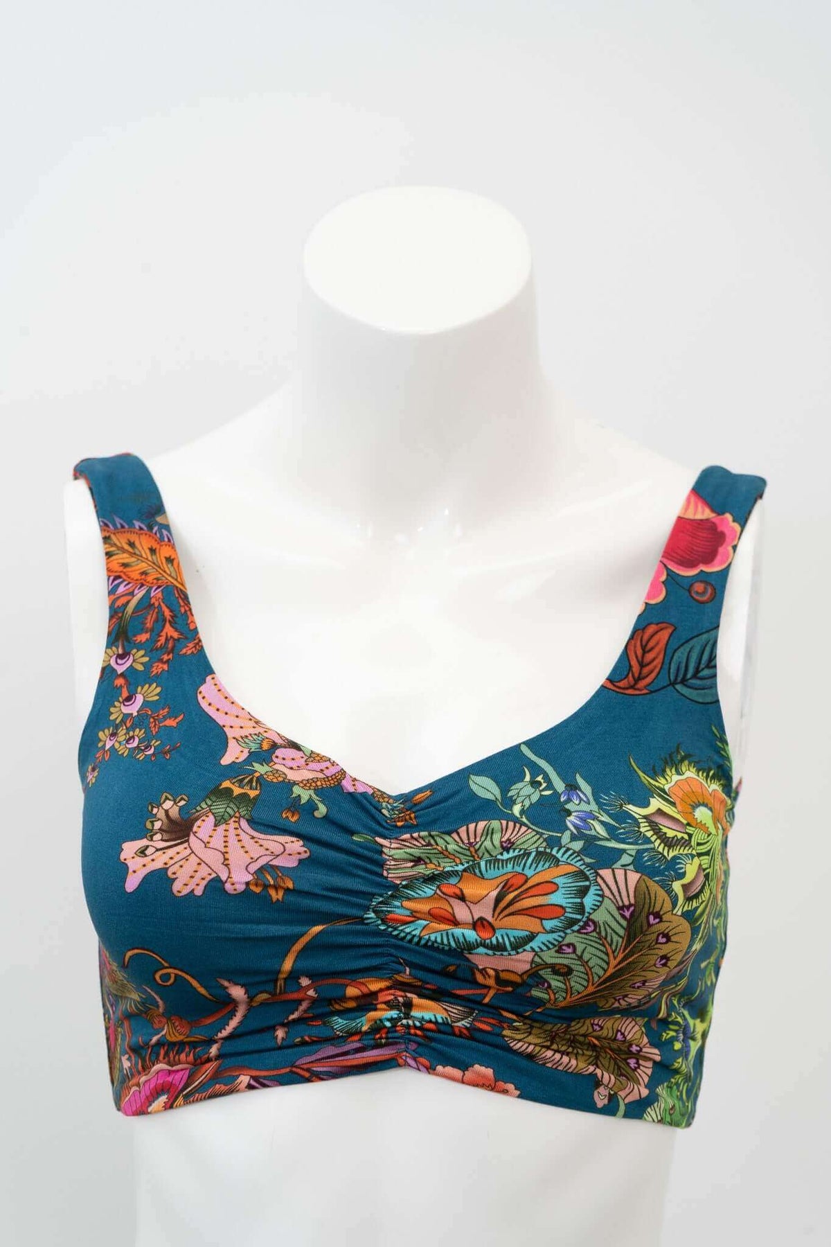 Close-up of teal floral crop top with cinched neckline on mannequin