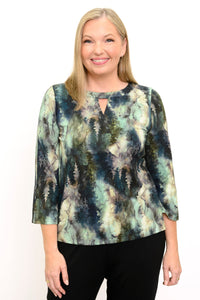Front view of a female model wearing a watercolor green top with long sleeves with black pants, against a white backdrop