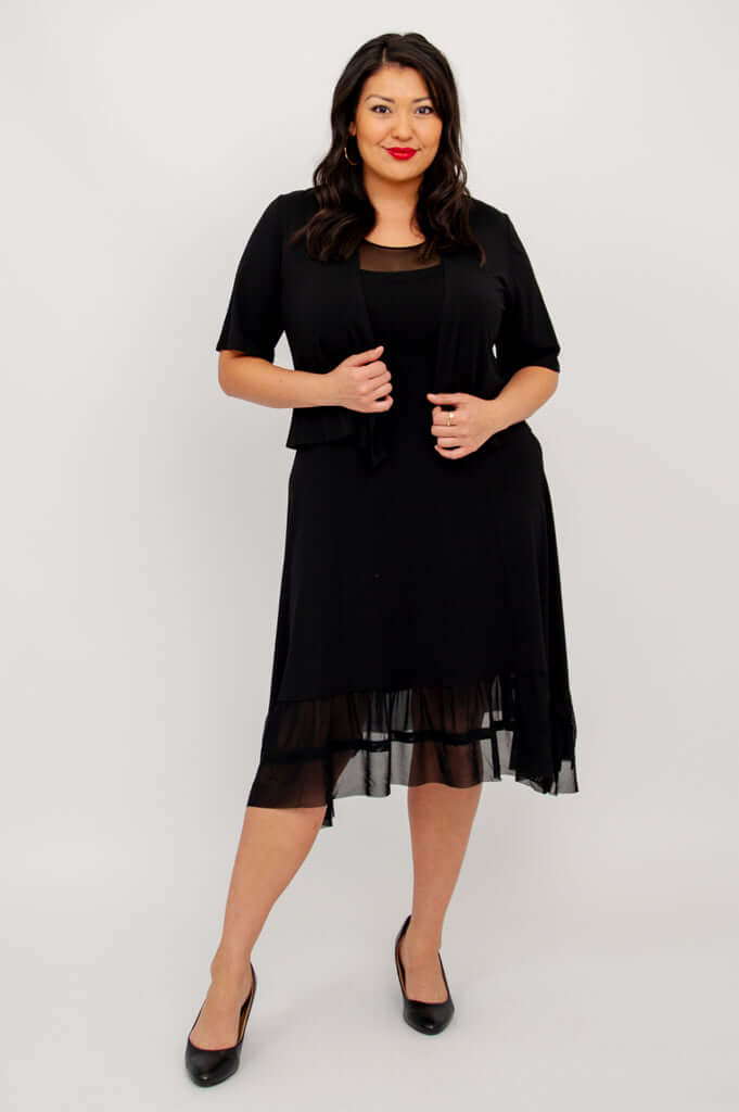 Model posing in black mesh hem dress and short sleeve black jacket