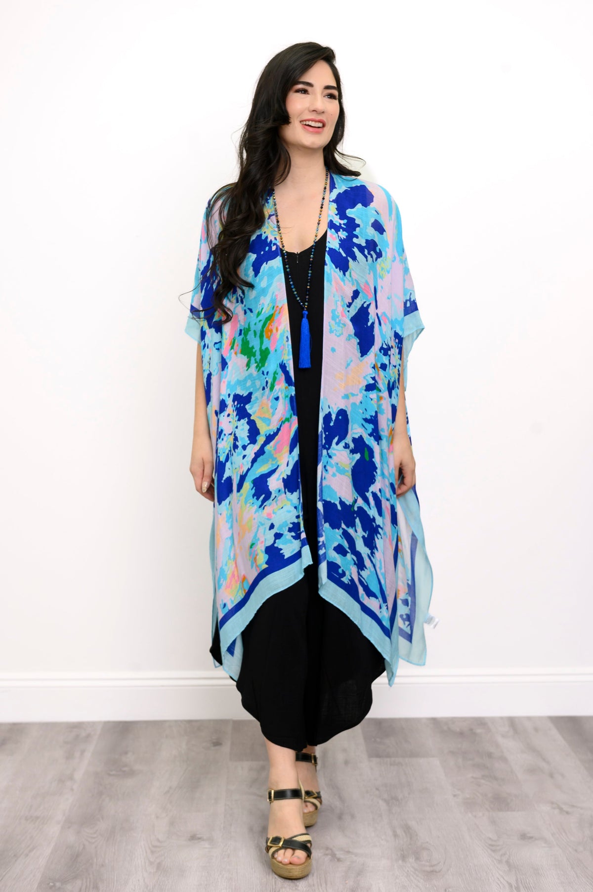 Front view of woman wearing a blue floral kimono on a black outfit against a white background