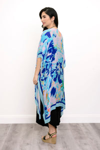 Back view of woman wearing a blue floral kimono on a black outfit against a white background