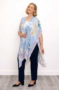 Side view of woman wearing a light blue floral kimono on a white top and navy pants against a white background