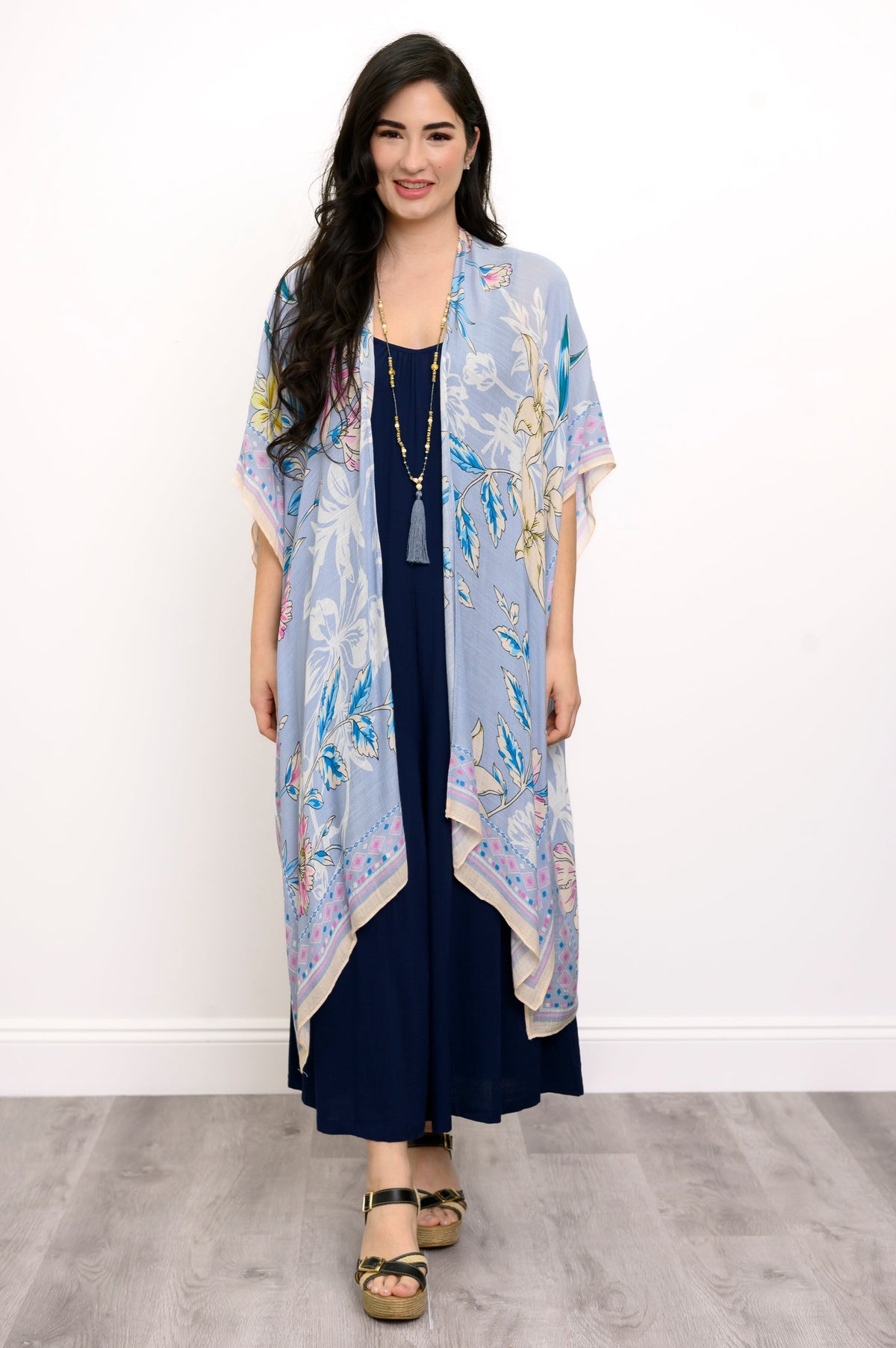 Front view of woman wearing a light blue floral kimono on a navy outfit against a white background