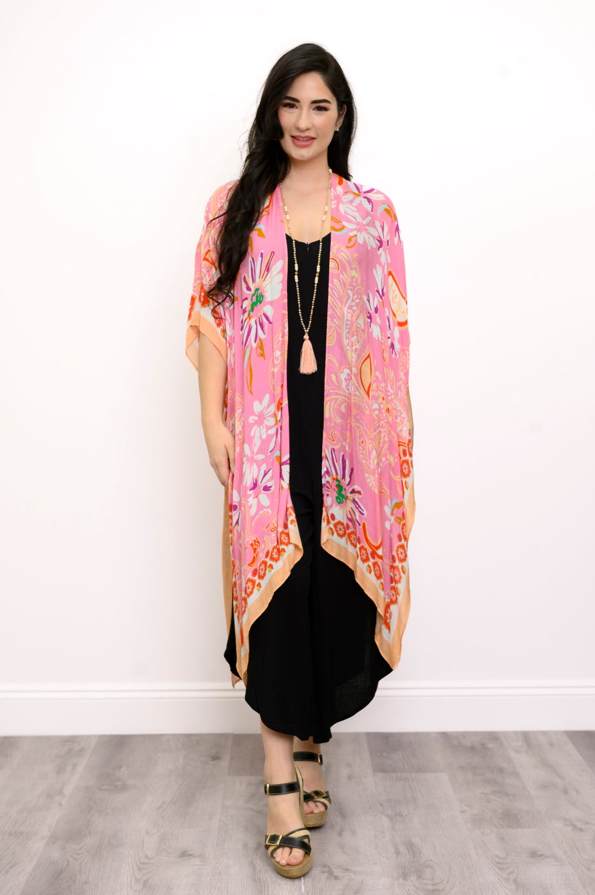 Front view of woman wearing a pink floral kimono on a black outfit against a white background