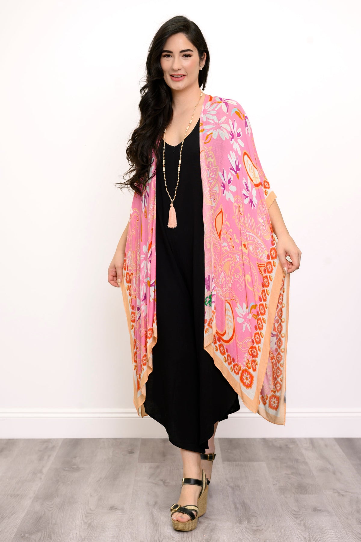 Front view of woman wearing a pink floral kimono on a black outfit against a white background
