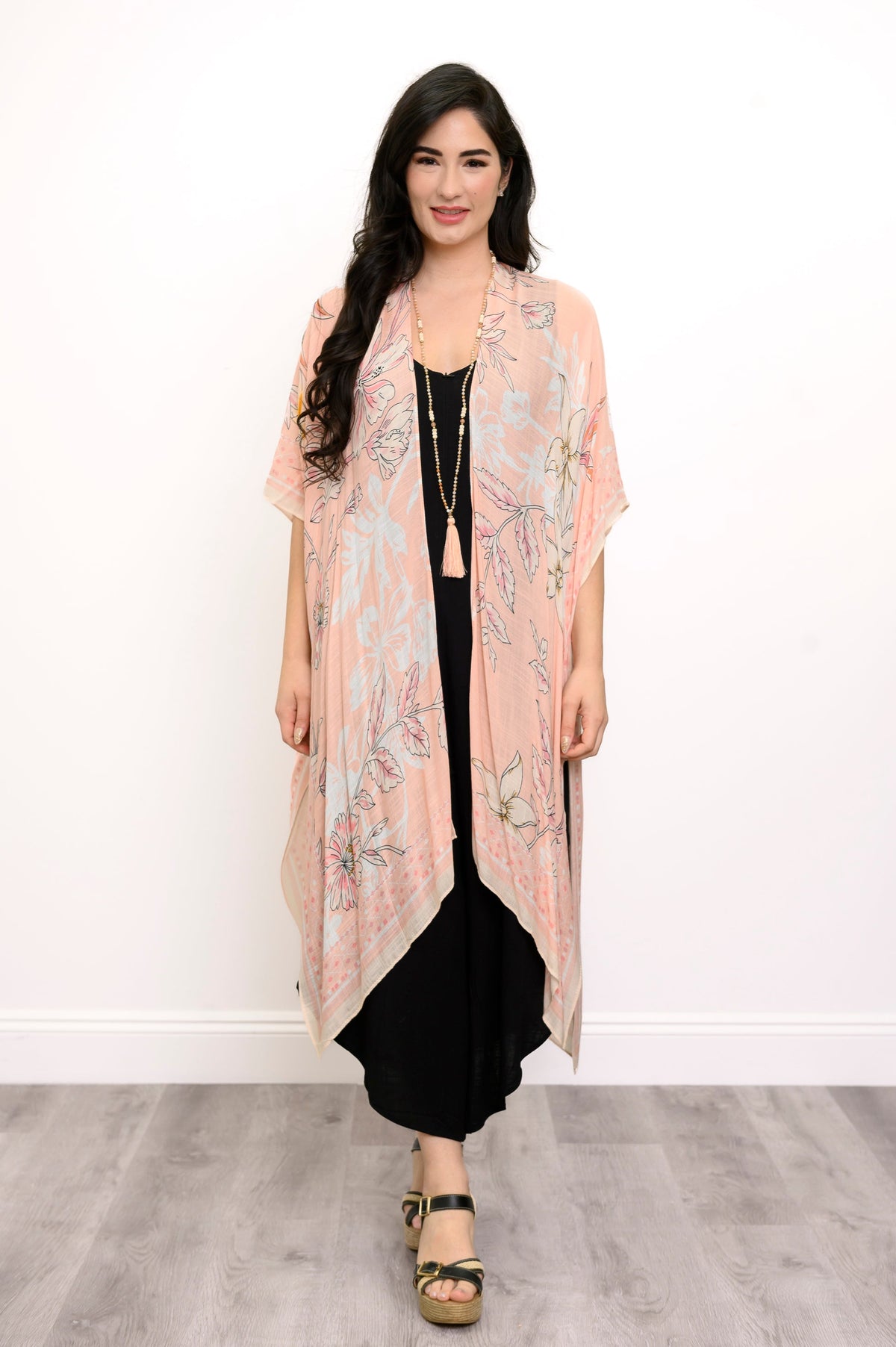 Front view of woman wearing pink floral patterned kimono on a black outfit against a white background