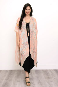Front view of woman wearing pink floral patterned kimono on a black outfit against a white background