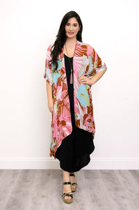 Front view of woman wearing multicolor tropcial patterned kimono on a black outfit against a white background