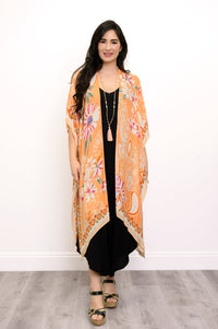 Front view of woman wearing orange floral patterned kimono on black outfit against a white background 