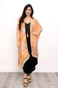 Front view of woman wearing orange floral patterned kimono on black outfit against a white background 