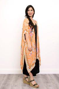 Side view of woman wearing orange floral patterned kimono on black outfit against a white background 
