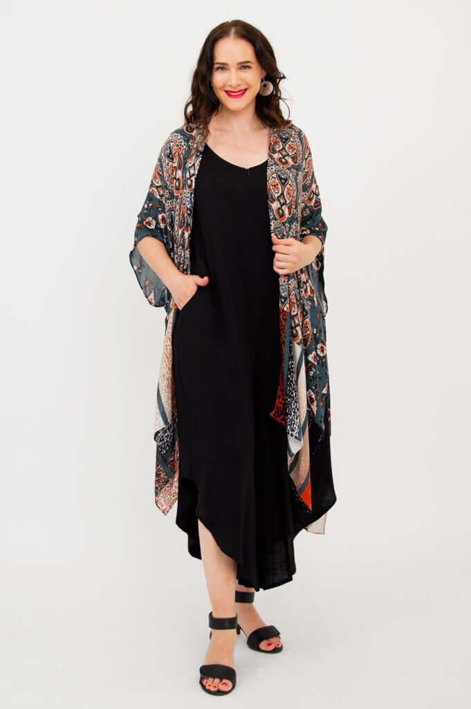 Model with hand in pocket, wearing Darcy kimono wrap open over a black dress