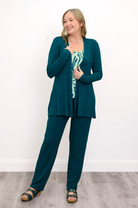 Front view, woman wearing a green sweater, green patterned top, and green pants on a white background