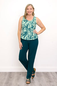 Front view of Woman wearing a green floral patterned sleeveless top and green pants against a white background