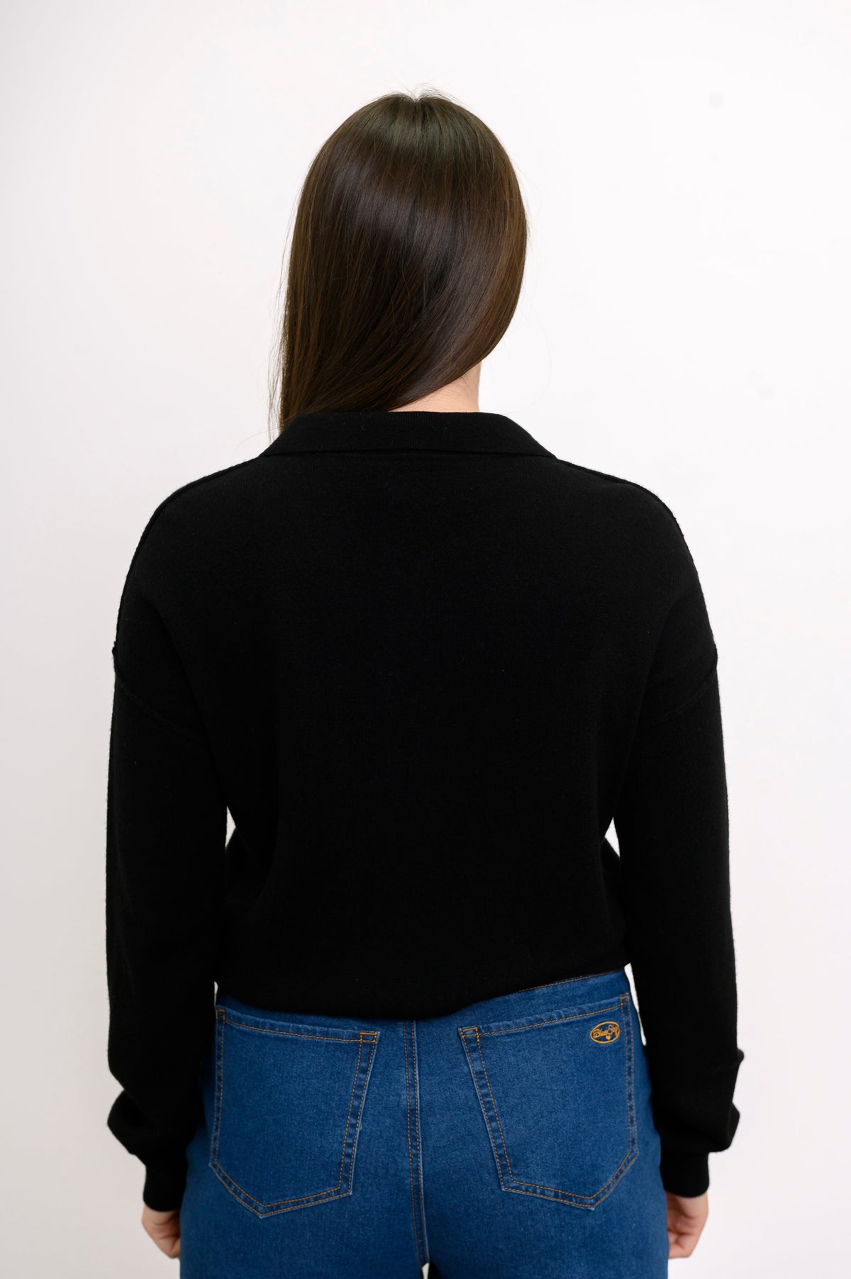 Back view of relaxed fit black cashmere sweater with ribbed hem styled with jeans