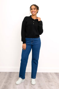 Front view of model wearing black cashmere sweater with collar and button details