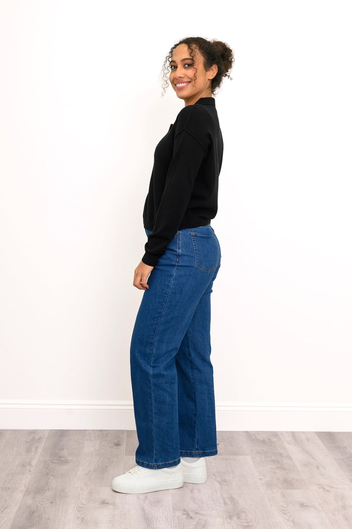 Model posing to the side in black cashmere sweater with long sleeves and relaxed fit