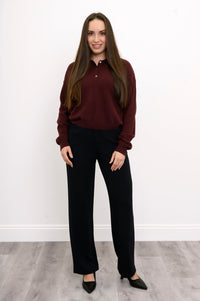 Full body front view of woman wearing loose fitting cashmere sweater with ribbed hem and dark cherry color