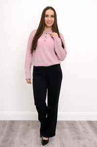 Woman posing with her hand on the collar of her button up blush pink cashmere sweater