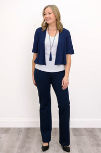Front view, woman wearing navy blue jacket, white top, blue necklace, and blue pants against a white background