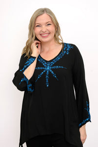 Front view of woman wearing a black top with blue embellishments against a white background