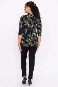 Back view of a woman wearing the black and green abstract patterned top, black pants, and heels