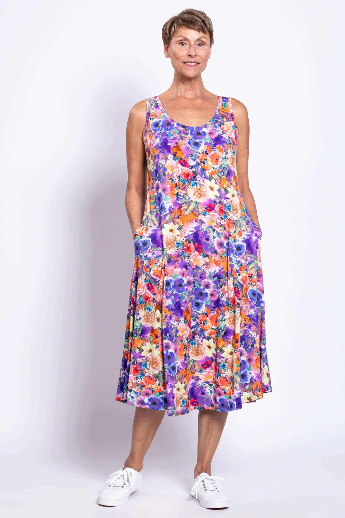 Woman showing side pockets on a colorful floral tank dress