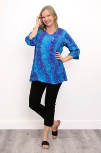 Front view of woman wearing a blue patterned blouse and black pants against a white background