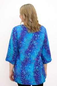 Back view of woman wearing a blue patterned blouse on a white background