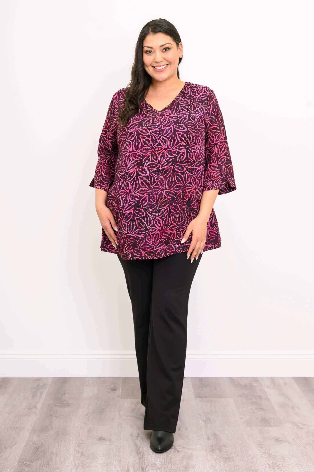 Front view of woman in Evelyn Top with pink botanical pattern and black pants