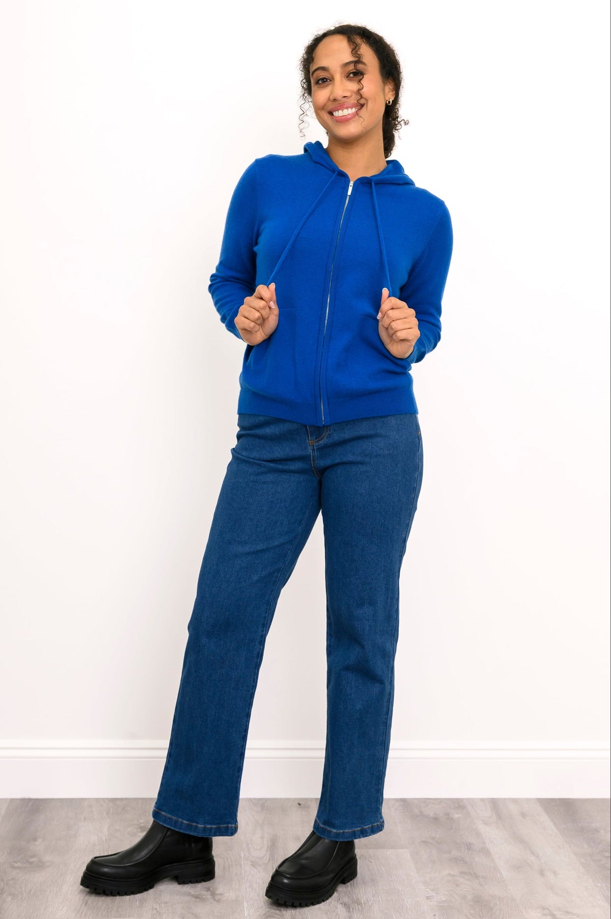 Full body front view of woman in a cobalt blue cashmere hoodie with straight leg jeans