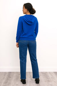 Full body back view of woman wearing bright blue hoodie with jeans and black boots