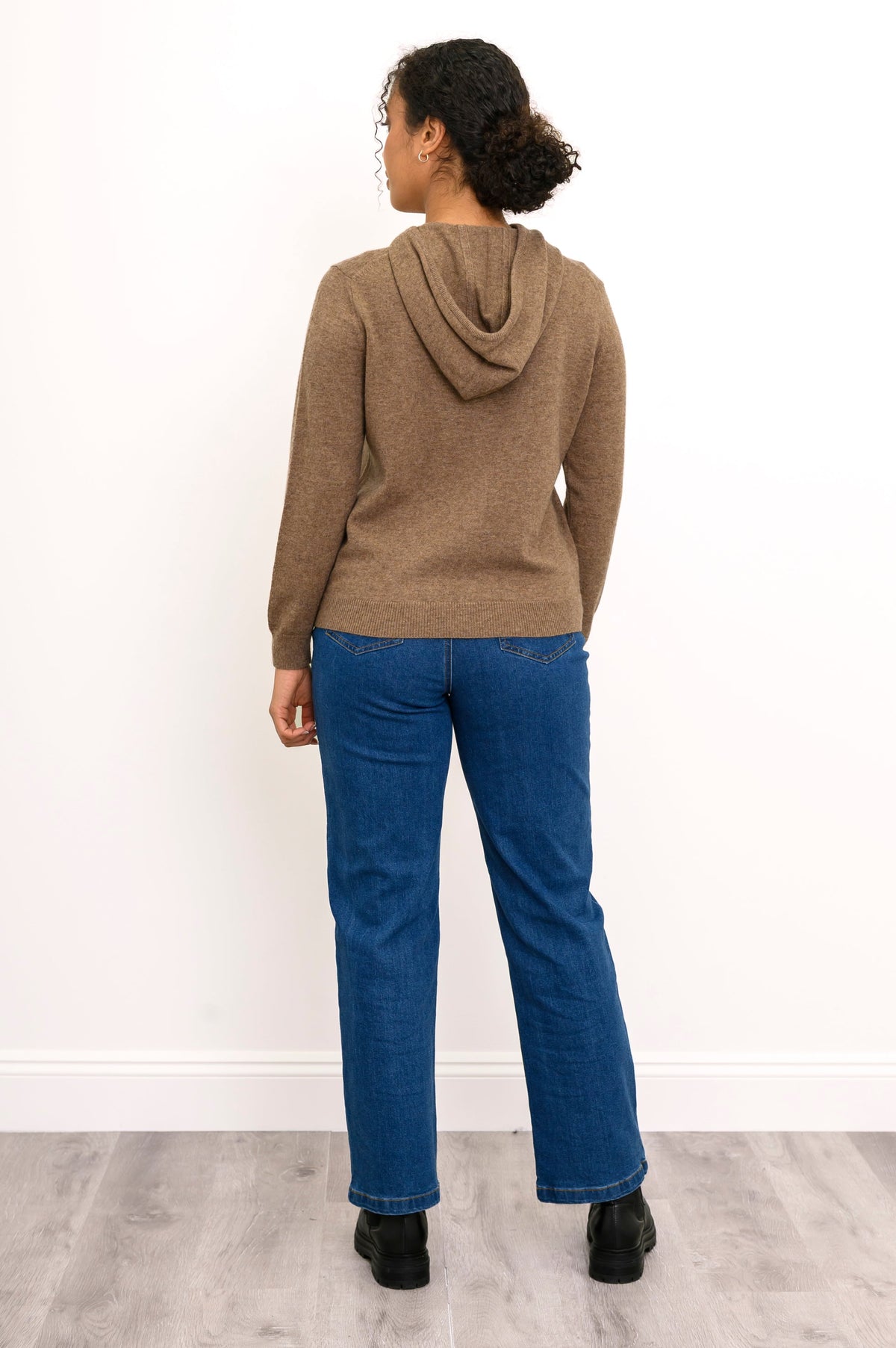Full body back view of woman wearing brown hoodie with jeans and black boots