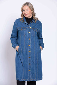 Close up view of a woman wearing a knee length blue denim coat with her hands resting in pockets.