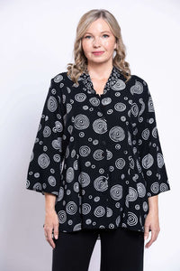 Front view of model wearing black blouse with white circular pattern