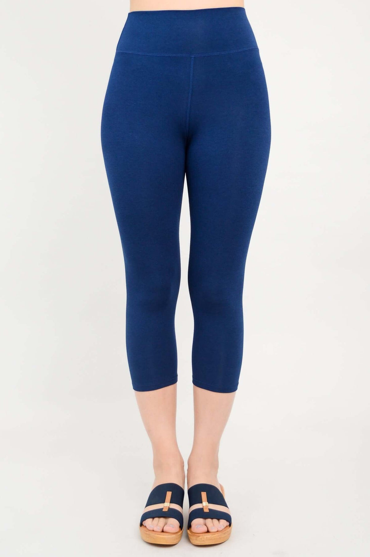 Front view of woman wearing navy blue Riley Capri Legging and wedge sandals