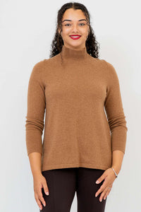 Front view of a woman wearing a camel brown mock neck sweater and dark pants