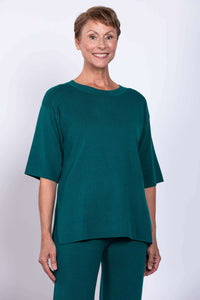 Studio portrait of a model in a teal green viscose cotton blend short sleeve knit pullover top.