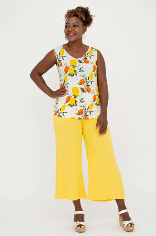 Front view of a woman wearing a V-Neck Tank with vibrant lemon and orange print, styled with yellow pants