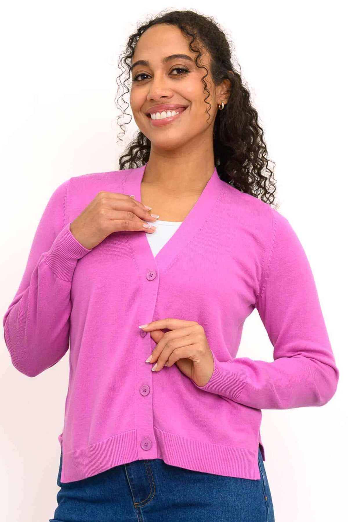 Front view of woman wearing pink V-neck button-up cardigan with ribbed cuffs