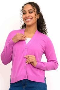Front view of woman wearing pink V-neck button-up cardigan with ribbed cuffs