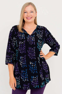 Front view of woman wearing a black batik blouse with purple and blue accents