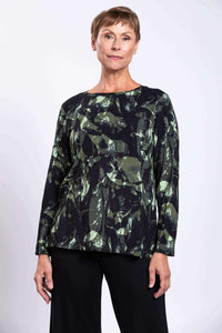 Woman wearing a long-sleeve forest abstract print top with black pants, front view